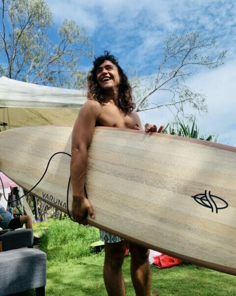 Billy Otto holding a Varuna wooden surfboard